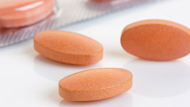 Orange lozenge shaped pills next to a pill blister pack
